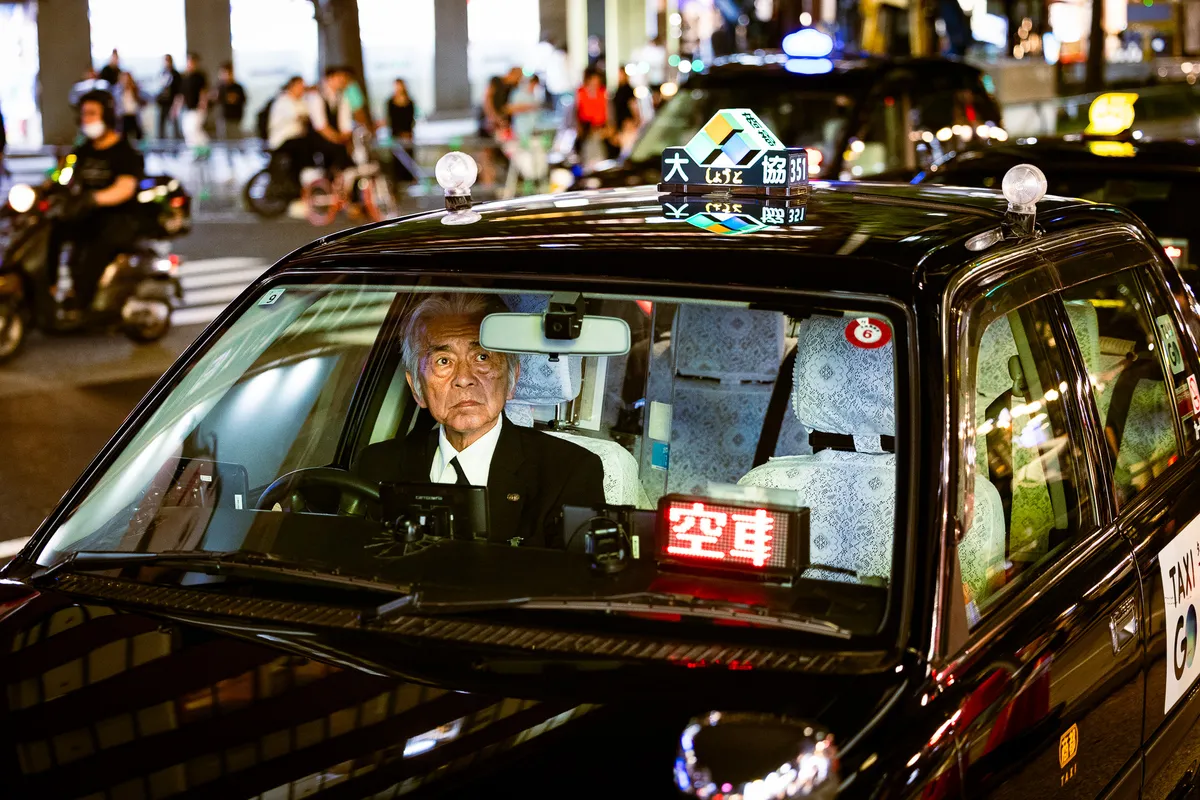 Taxi driver waiting in a neon-lit street at night
